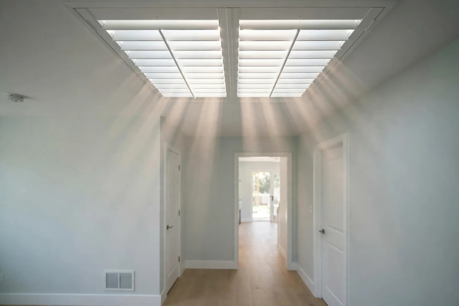 Whole-house fan louvered shutter with daylight streaming through